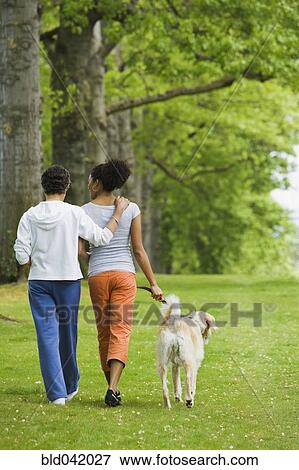 Stock Photo - African American mother and adult daughter walking dog. Fotosearch