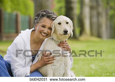 Stock Image - African American woman hugging dog. Fotosearch