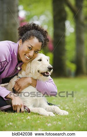 Stock Photo - African American woman hugging dog. Fotosearch