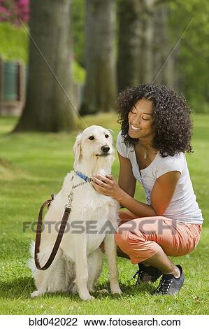 Stock Image - African American woman petting dog. Fotosearch