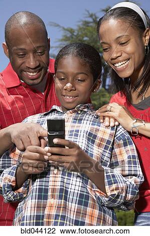 Stock Image - African family looking at cell phone. Fotosearch