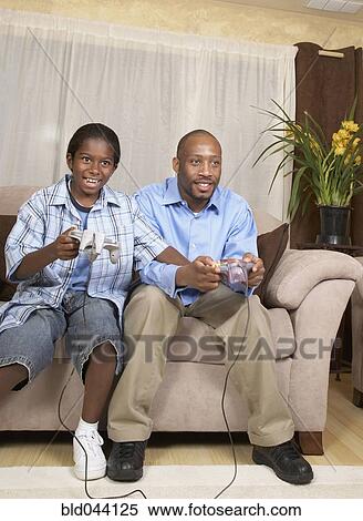 African father and son playing video games View Large Photo Image Stock Photography - African father and son playing video games. Fotosearch