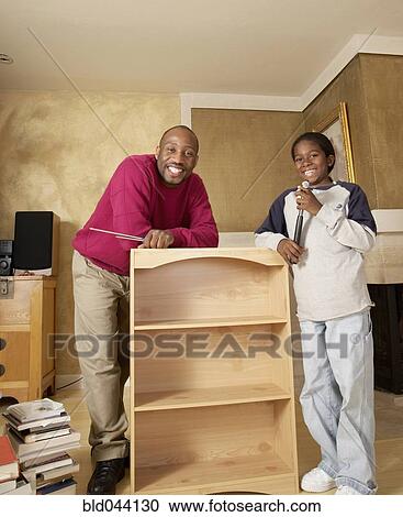 Stock Image - African father and son putting furniture together. Fotosearch