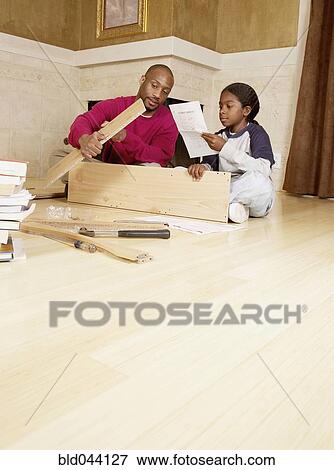 Stock Photo - African father and son putting furniture together. Fotosearch