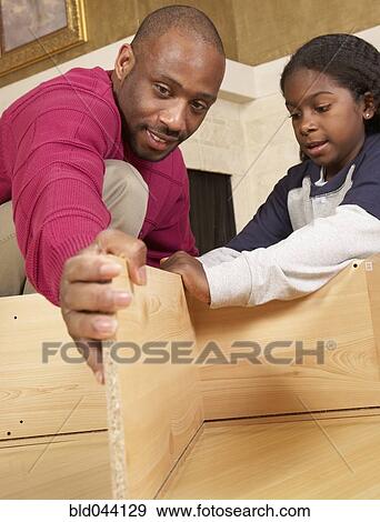 Stock Photo - African father and son putting furniture together. Fotosearch