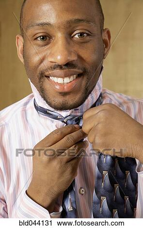 Stock Image - African man putting on tie. Fotosearch