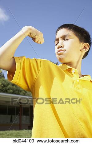 Stock Photo - Asian boy flexing muscles. Fotosearch