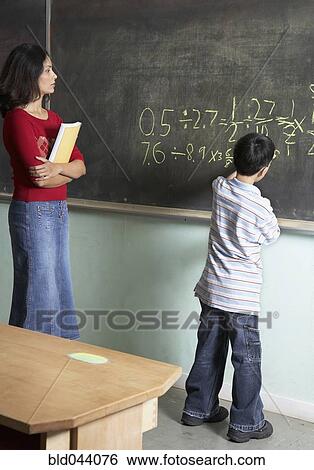 Stock Photograph - Asian boy writing on blackboard. Fotosearch