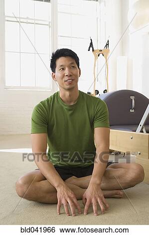 Stock Photograph - Asian man sitting in exercise studio. Fotosearch