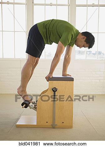 Asian man stretching on exercise equipment View Large Photo Image Stock Image - Asian man stretching on exercise equipment. Fotosearch