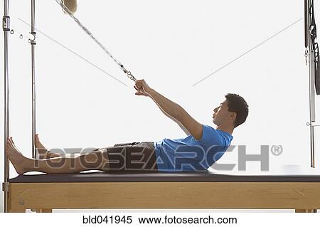 Stock Photography - Asian man stretching on exercise equipment. Fotosearch