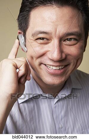 Asian man wearing hands free device View Large Photo Image Stock Image - Asian man wearing hands free device. Fotosearch