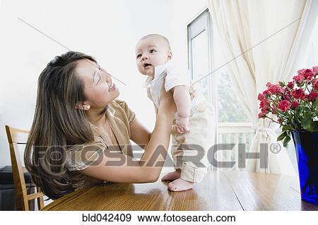 Asian mother smiling at baby View Large Photo Image Stock Photo - Asian mother smiling at baby. Fotosearch