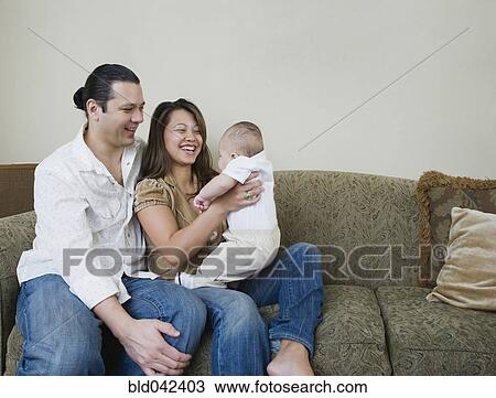 Stock Image - Asian parents smiling at baby. Fotosearch