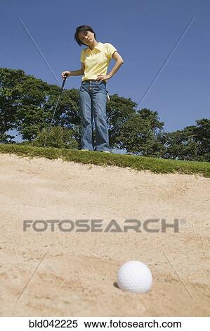 Asian woman looking at golf ball in sand trap View Large Photo Image Stock Photography - Asian woman looking at golf ball in sand trap. Fotosearch