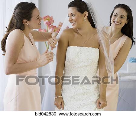 Stock Image - Hispanic bride having veil adjusted. Fotosearch