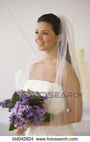 Picture - Hispanic bride holding bouquet of flowers. Fotosearch
