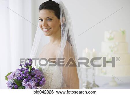 Stock Photograph - Hispanic bride holding bouquet of flowers. Fotosearch
