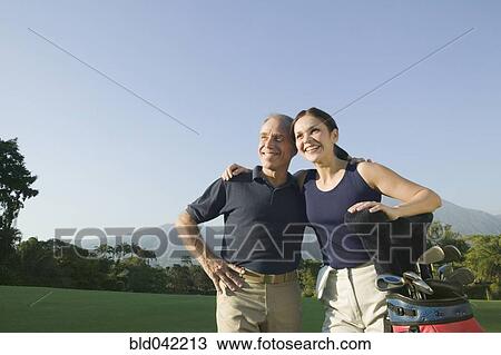 Stock Image - Hispanic couple on golf course. Fotosearch