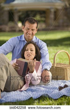 Stock Photo - Hispanic couple reading on picnic blanket. Fotosearch