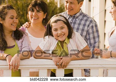 Stock Photo - Hispanic family leaning on porch railing. Fotosearch