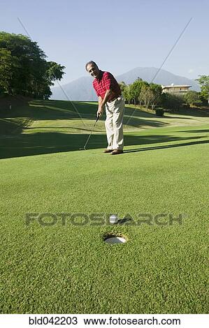 Stock Image - Hispanic man playing golf. Fotosearch
