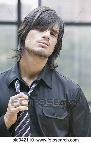 Stock Image - Hispanic man pulling on tie. Fotosearch