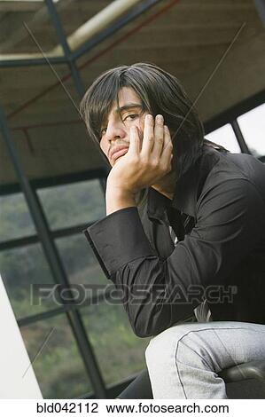 Stock Image - Hispanic man with chin in hand. Fotosearch