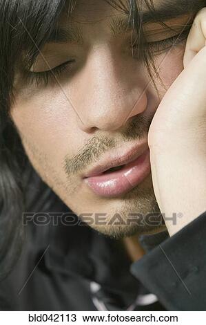 Stock Image - Hispanic man with chin in hand. Fotosearch