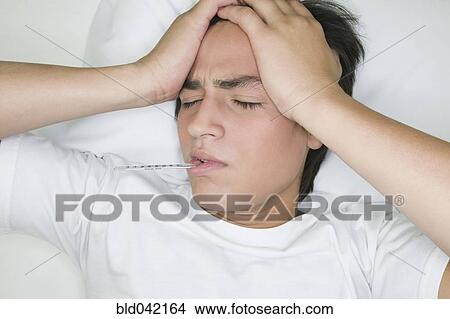 Picture - Hispanic man with thermometer in mouth. Fotosearch