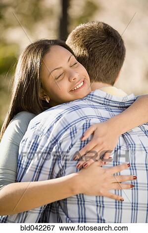 Stock Photo - Hispanic woman hugging boyfriend. Fotosearch