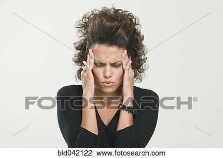 Stock Image - Hispanic woman rubbing temples. Fotosearch