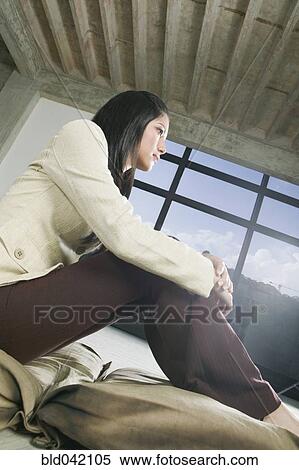 Stock Photography - Hispanic woman sitting with hands on knees. Fotosearch