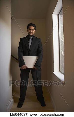 Indian businessman holding laptop View Large Photo Image Stock Photo - Indian businessman holding laptop. Fotosearch