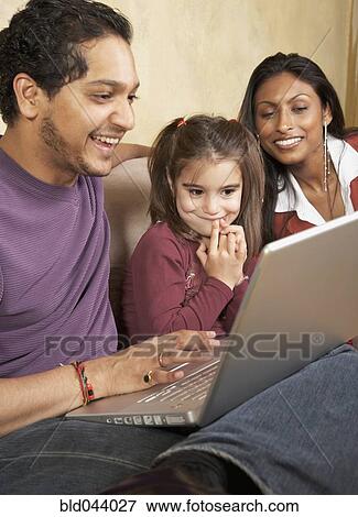 Stock Photo - Indian family looking at laptop. Fotosearch