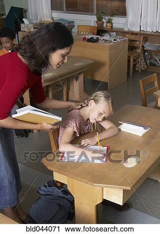 Stock Image - Indian female teacher helping student. Fotosearch
