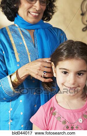 Indian grandmother fixing granddaughter's hair View Large Photo Image Stock Photo - Indian grandmother fixing granddaughter's hair. Fotosearch