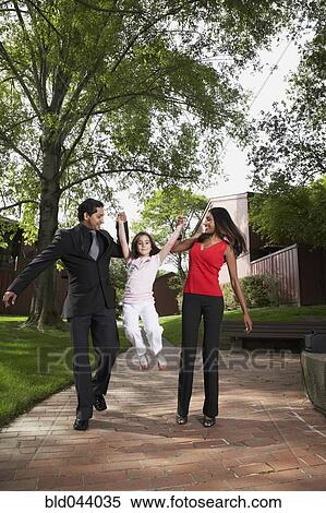 Stock Photography - Indian parents swinging daughter by hands. Fotosearch
