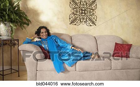 Indian woman sitting on sofa View Large Photo Image Stock Photograph - Indian woman sitting on sofa. Fotosearch