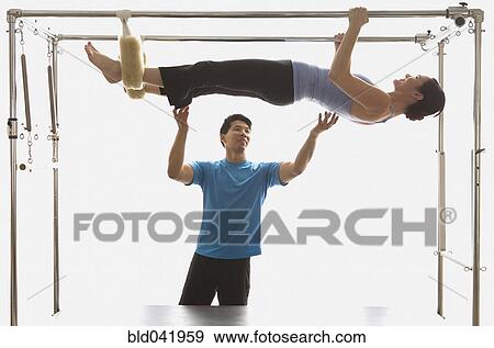 Instructor spotting woman on exercise equipment View Large Photo Image Stock Photo - Instructor spotting woman on exercise equipment. Fotosearch