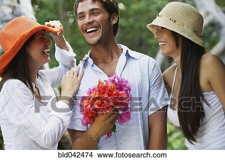 Man holding flowers between two women View Large Photo Image Picture - Man holding flowers between two women. Fotosearch