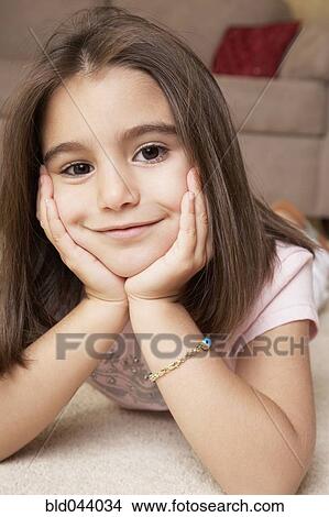 Picture - Middle Eastern girl laying on floor. Fotosearch