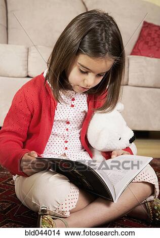 Picture - Middle Eastern girl reading on floor. Fotosearch