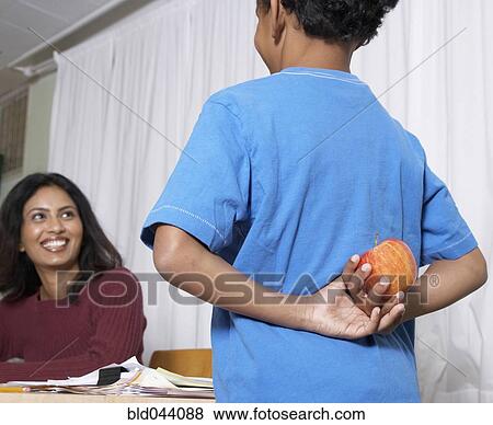 Stock Photo - Mixed Race boy giving apple to teacher. Fotosearch