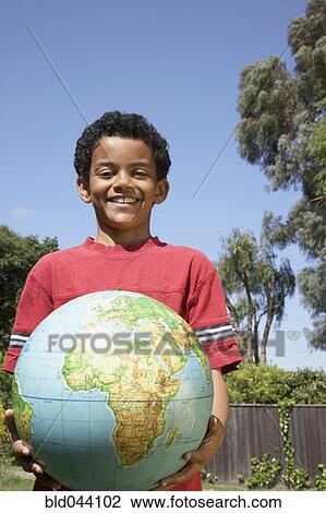 Stock Image - Mixed Race boy holding globe. Fotosearch
