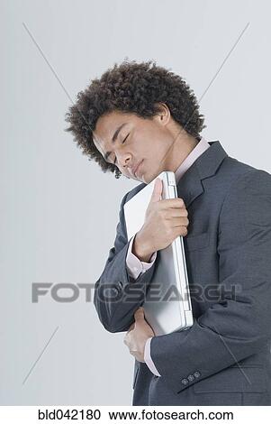 Mixed Race businessman hugging laptop View Large Photo Image Stock Image - Mixed Race businessman hugging laptop. Fotosearch
