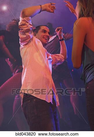 Stock Image - Multi-ethnic couple dancing at nightclub. Fotosearch