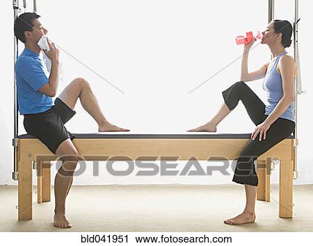 Stock Image - Multi-ethnic friends sitting on exercise equipment. Fotosearch