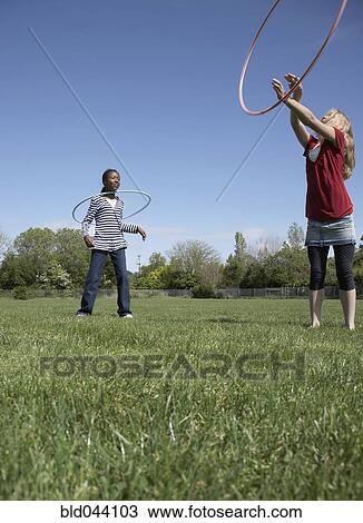 Stock Image - Multi-ethnic girls playing with hula hoops. Fotosearch