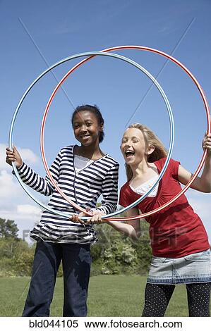 Stock Photography - Multi-ethnic girls playing with hula hoops. Fotosearch